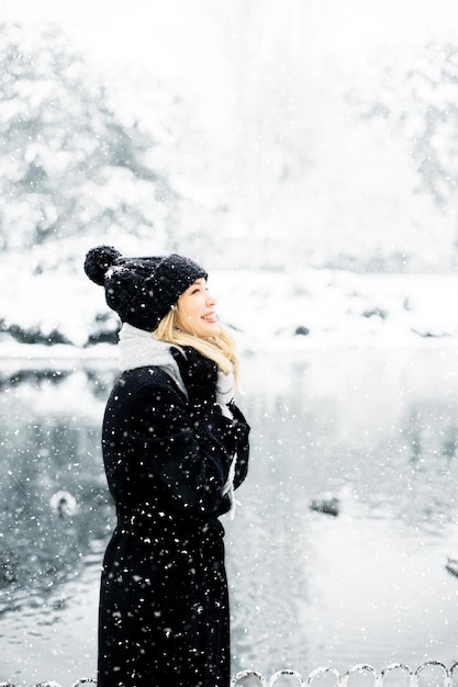 雪の中で楽しんでいる暖かい服装の若い女性