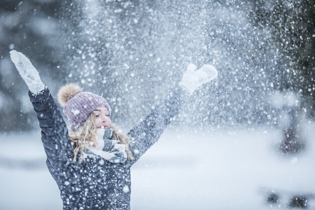 暖かい服を着た若い女性が雪の中を楽しんでいます。