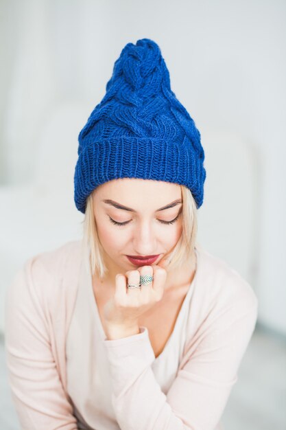 Young woman in warm dark blue hand knitted hat at home