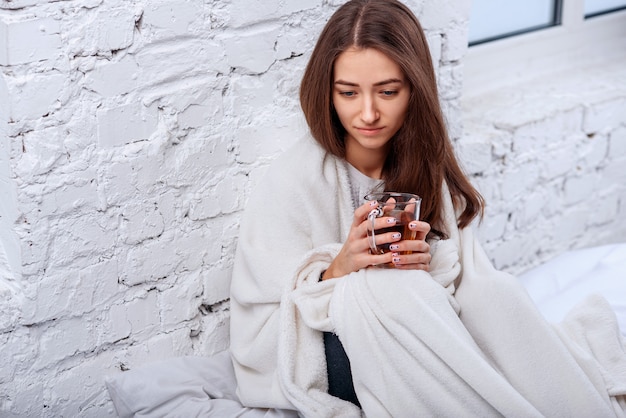 young woman in warm plaid with hot cup of tea in hands