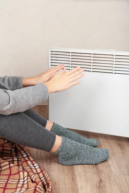 young woman in warm socks near electric heater at home concept of heating season top view