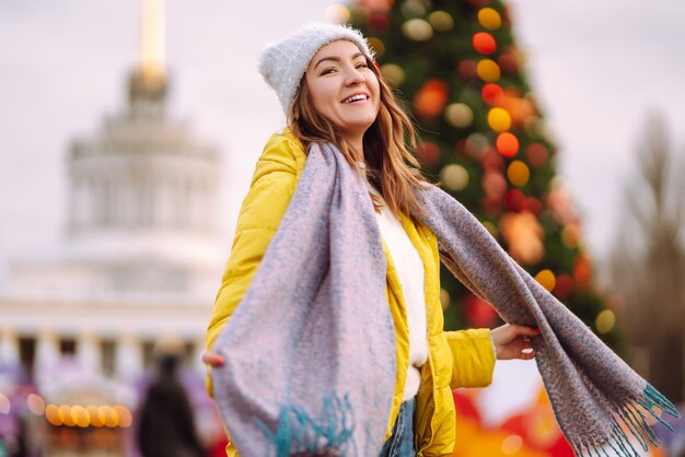 Young woman in warm winter clothing posing at festival. Winter holiday.