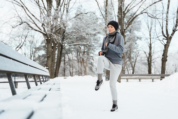 Giovane donna che si scalda prima del suo allenamento di jogging durante l'inverno e la giornata nevosa