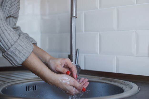 Young woman washes her hands with soap to prevent coronavirus infection