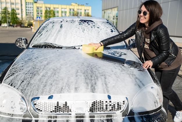 Young woman washing car at selfservice carwash