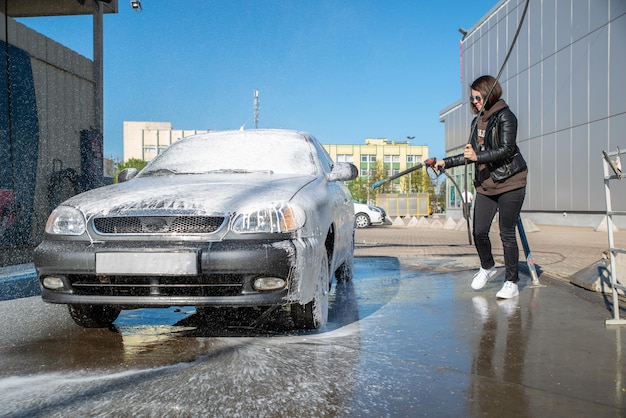 Young woman washing car at selfservice carwash