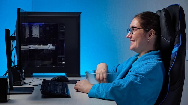 Young woman watches stream with computer and eats popcorn