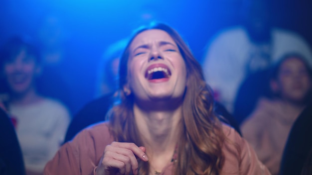 Young woman watching comedy movie in cinema Happy girl laughing on funny moment