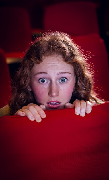 Young woman watching a scary film