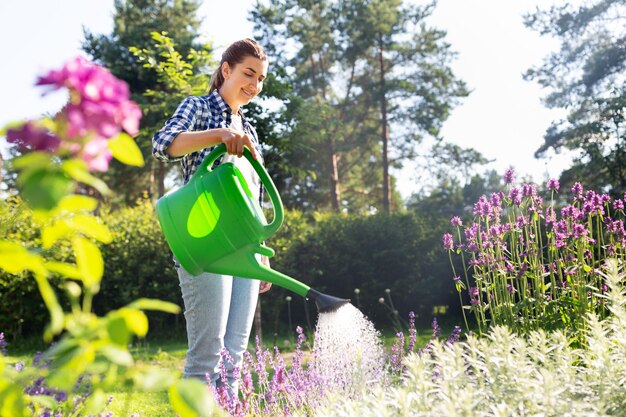 庭で花に水を注ぐ若い女性