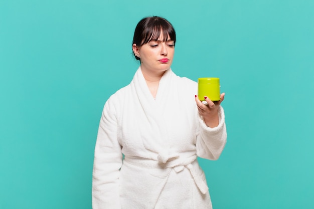 Young woman wearing bathrobe feeling sad, upset or angry and looking to the side with a negative attitude, frowning in disagreement