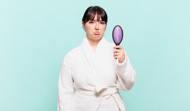 young woman wearing bathrobe feeling sad and whiney with an unhappy look, crying with a negative and frustrated attitude