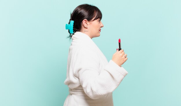 Young woman wearing bathrobe on profile view looking to copy space ahead, thinking, imagining or daydreaming