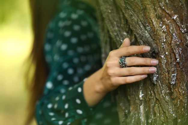 Young woman wearing beautiful silver ring with apatite gemstone near tree outdoors closeup