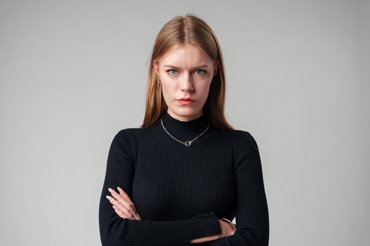 Фотография молодая женщина в черном топе и джинсах на сером фоне