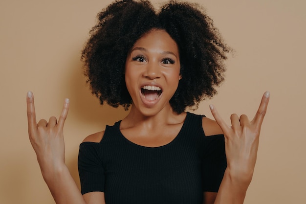 Young woman wearing black tshirt shouting with crazy facial expression doing rocknroll symbol