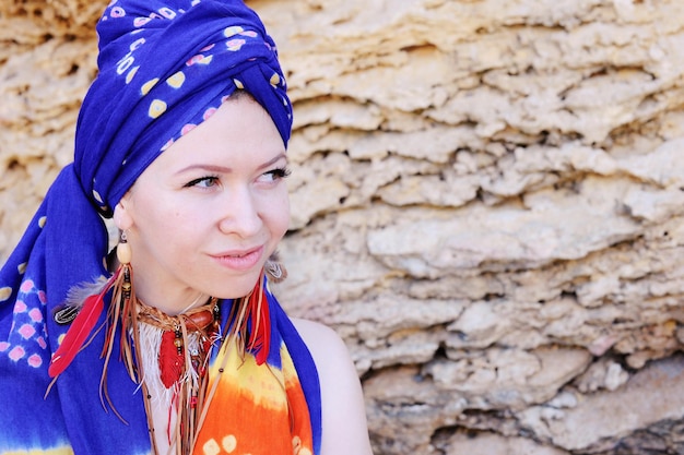 Foto giovane donna che indossa una sciarpa boho chic su una testa e una collana e orecchini di piume fatti a mano