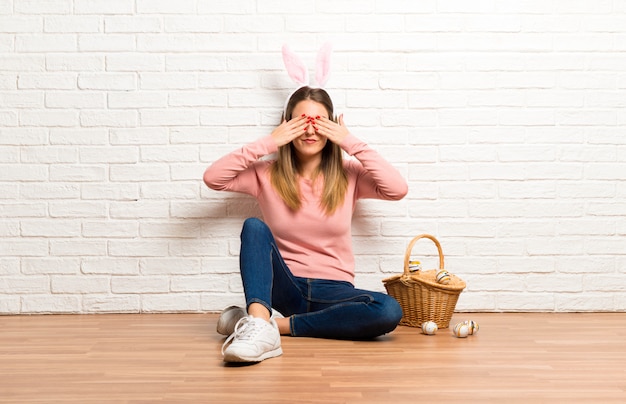 Молодая женщина носить уши кролика на пасхальные праздники, закрыв глаза руками