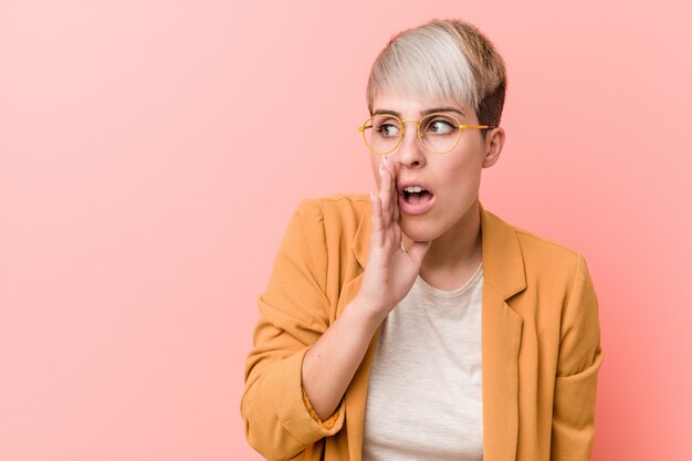 Young woman wearing a casual business clothes is saying a secret hot braking news and looking aside