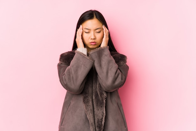 Young woman wearing a coat touching temples and having headache.