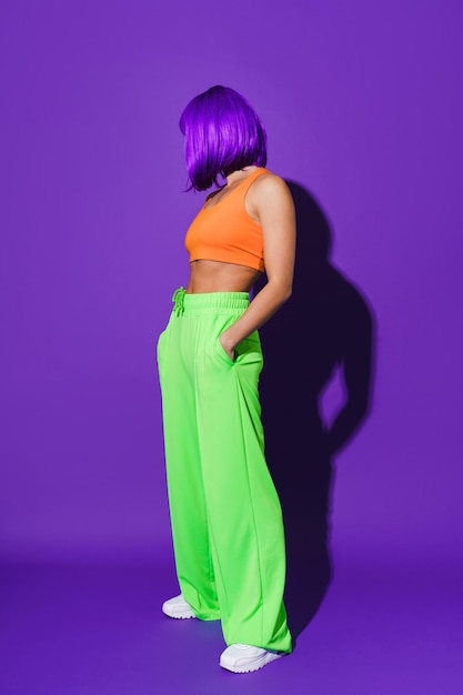 Young woman wearing colorful sportswear against purple background