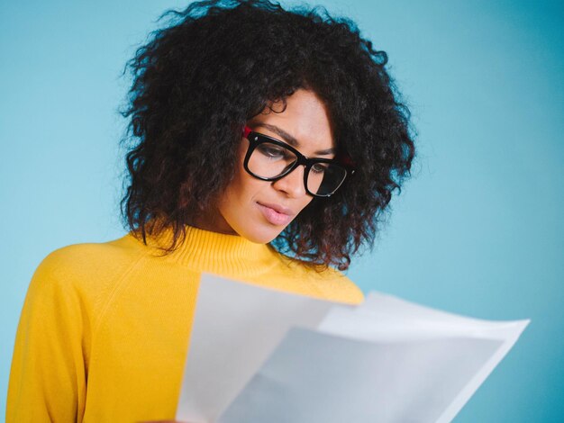 Photo young woman wearing eyeglasses reading documents against blue background