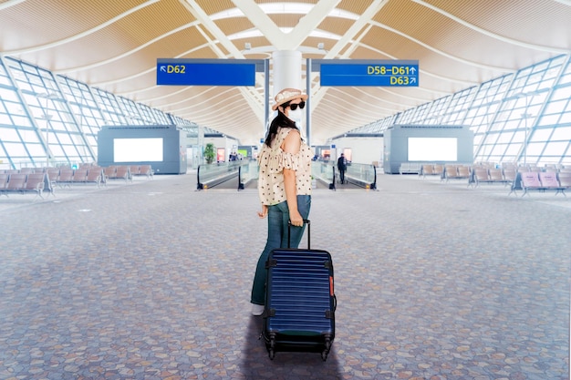 Молодая женщина в маске в терминале аэропорта