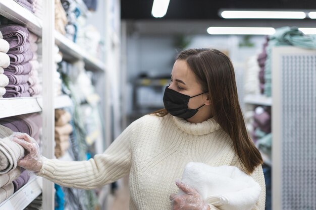 今日の人々のライフスタイルの概念の店でフェイスマスクと保護手袋を着用している若い女性