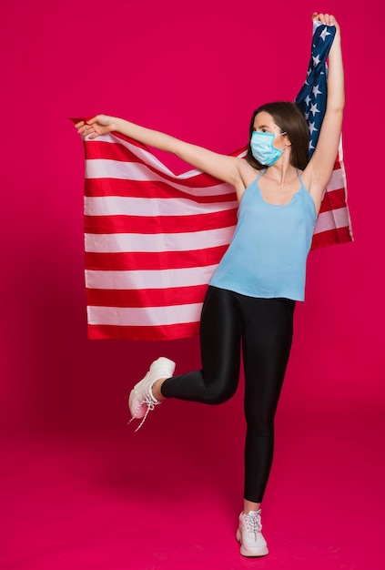 Молодая женщина в маске с флагом США на красном фоне
