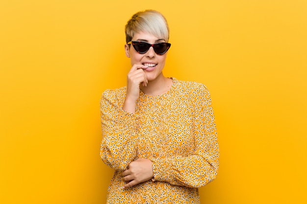 Young woman wearing a floral summer clothes relaxed thinking about something looking at a copy space.