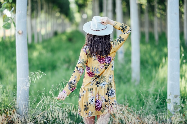 Foto giovane donna, che indossa un abito a fiori, tra gli alberi.