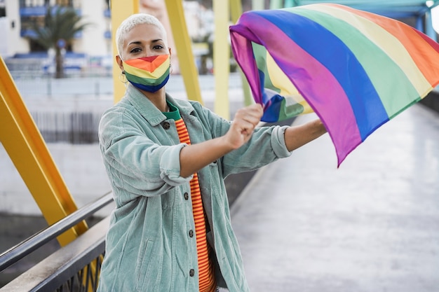 lgbt 깃발을 흔들며 게이 프라이드 마스크를 쓴 젊은 여자 - 얼굴에 초점