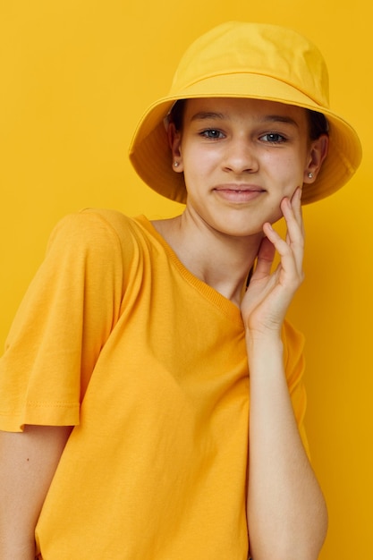 Young woman wearing hat against yellow background