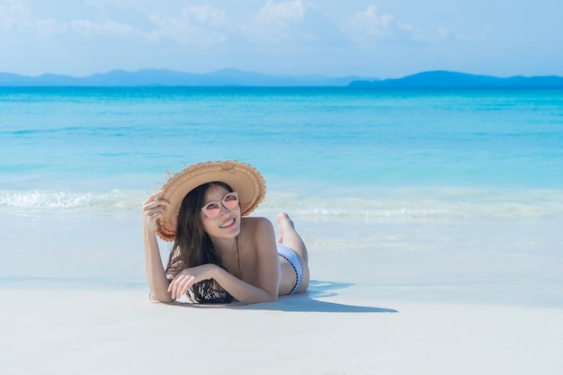 하늘을 배경으로 해변에서 모자를 입은 젊은 여성