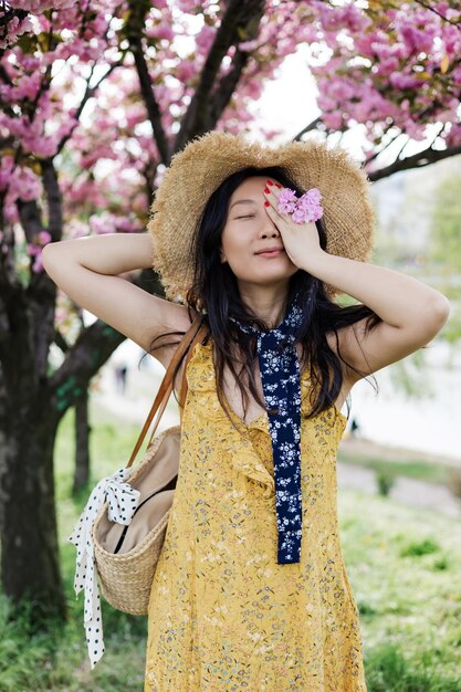 사진 꽃 나무 가 있는 정원 에서 모자 를 입은 젊은 여자