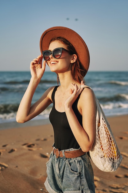 浜辺に立っている帽子をかぶった若い女性