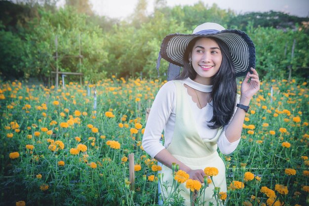 畑の花の中に立つとき帽子をかぶった若い女性