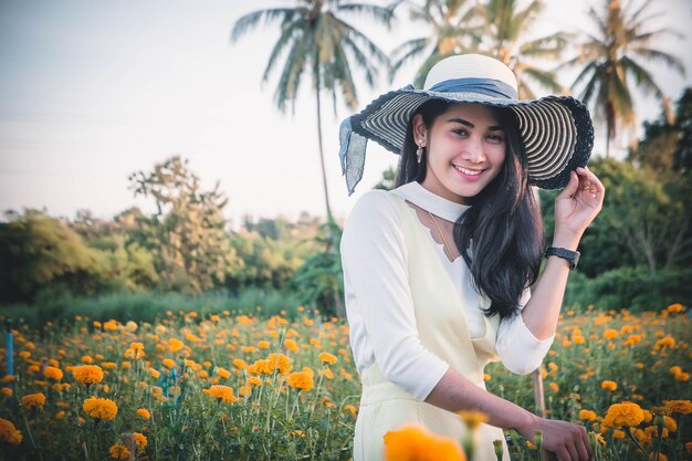 畑の花の中に立つとき帽子をかぶった若い女性