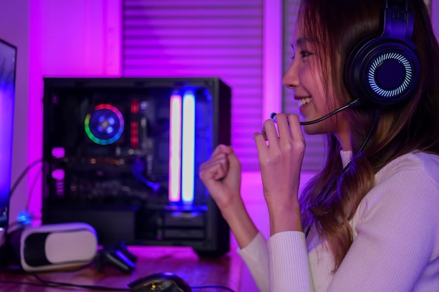 컴퓨터 게임을 하는 헤드폰을 착용 한 젊은 여성