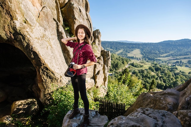 Young woman wearing hipster clothes with vintage photocamera traveling by the rocky mountains