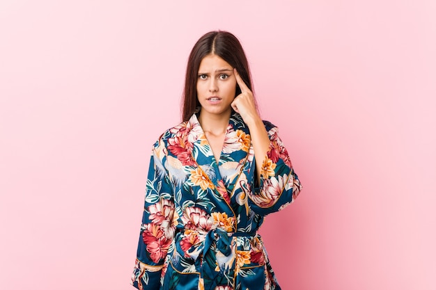 Young woman wearing a kimono pajama showing a disappointment gesture with forefinger