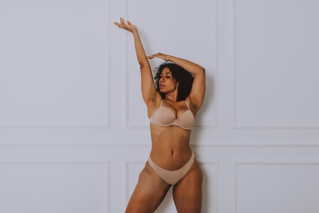 Young woman wearing lingerie standing against wall