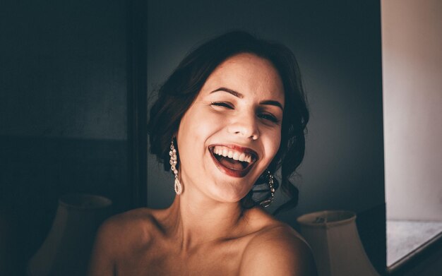 Photo young woman wearing lipstick and earrings while laughing at home