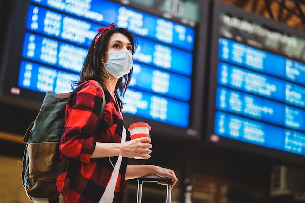 空港に立っている間マスクをかぶった若い女性が目をそらしている