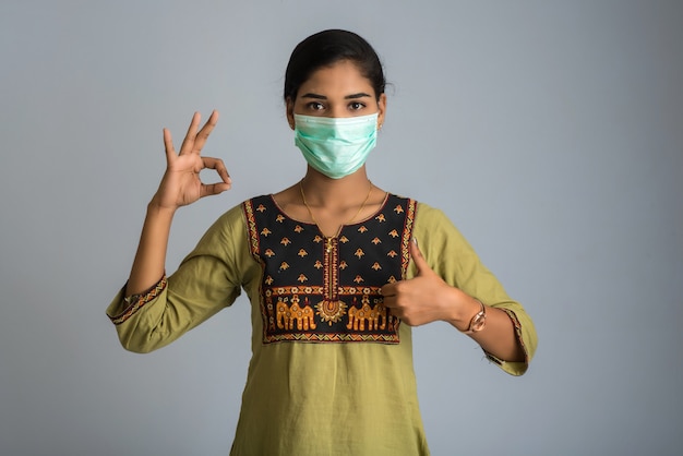 Young woman wearing medical face mask Showing sign. Woman wearing surgical mask for corona virus.