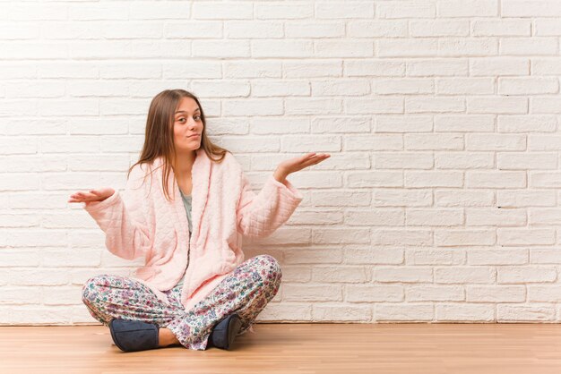 Young woman wearing pajama confused and doubtful