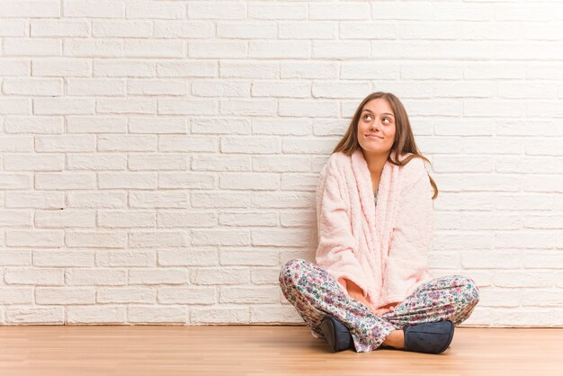 Young woman wearing pajama dreaming of achieving goals and purposes