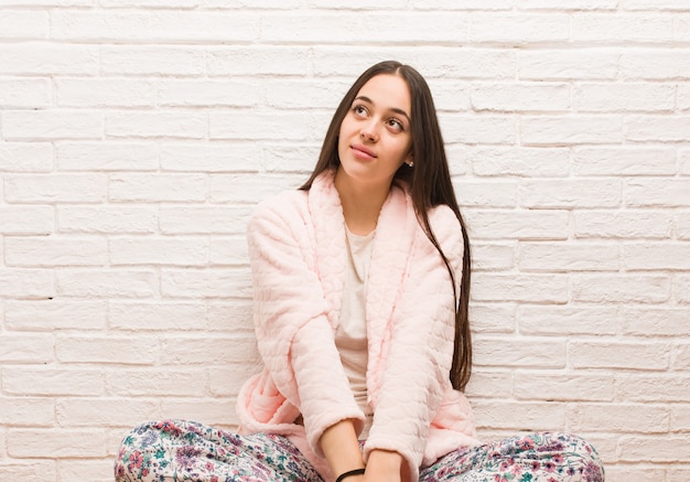 Young woman wearing pajama dreaming of achieving goals and purposes