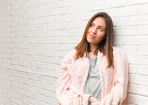 Young woman wearing pajama dreaming of achieving goals and purposes