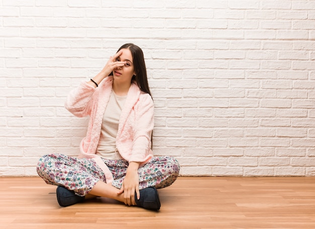 Young woman wearing pajama embarrassed and laughing at the same time